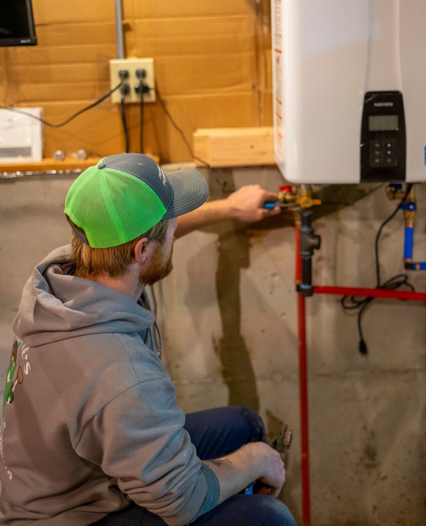 A man is fixing a water heater in a basement.