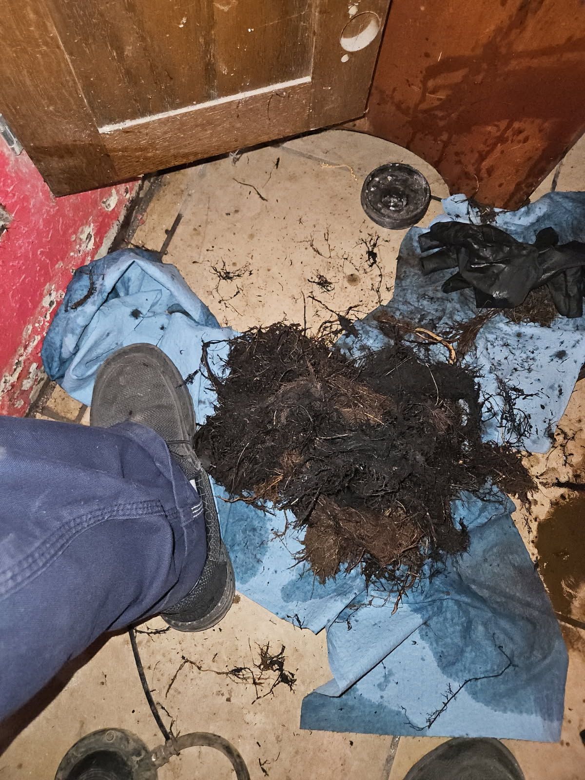 A person is standing next to a pile of dirt on the floor.