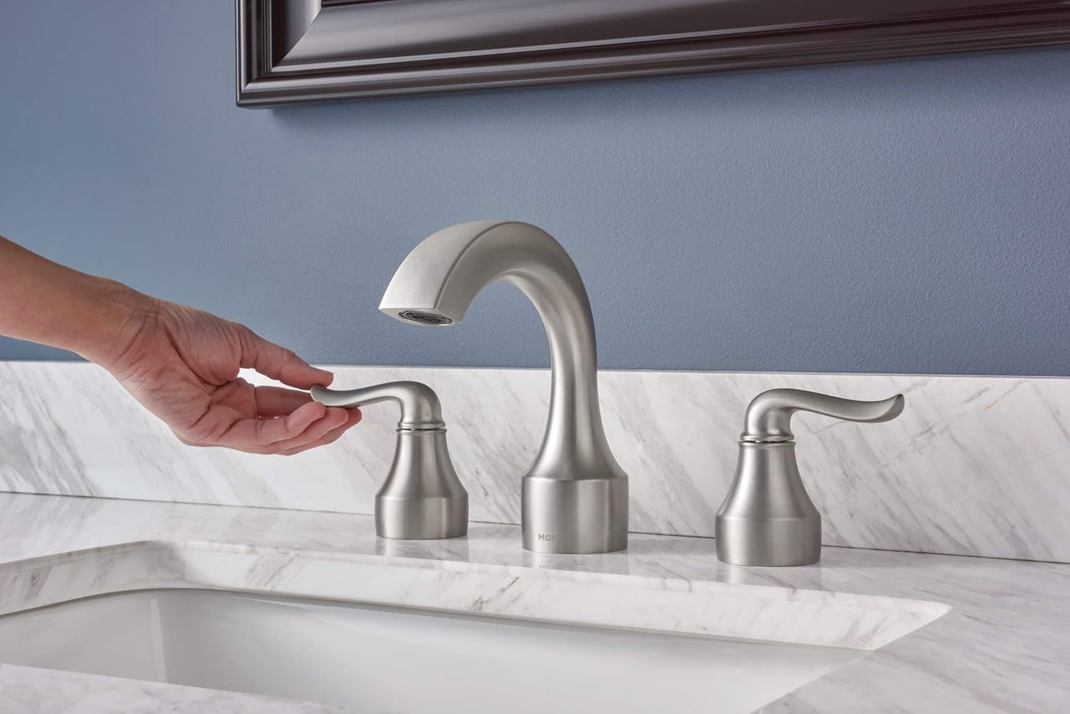 A person is adjusting a faucet on a bathroom sink.