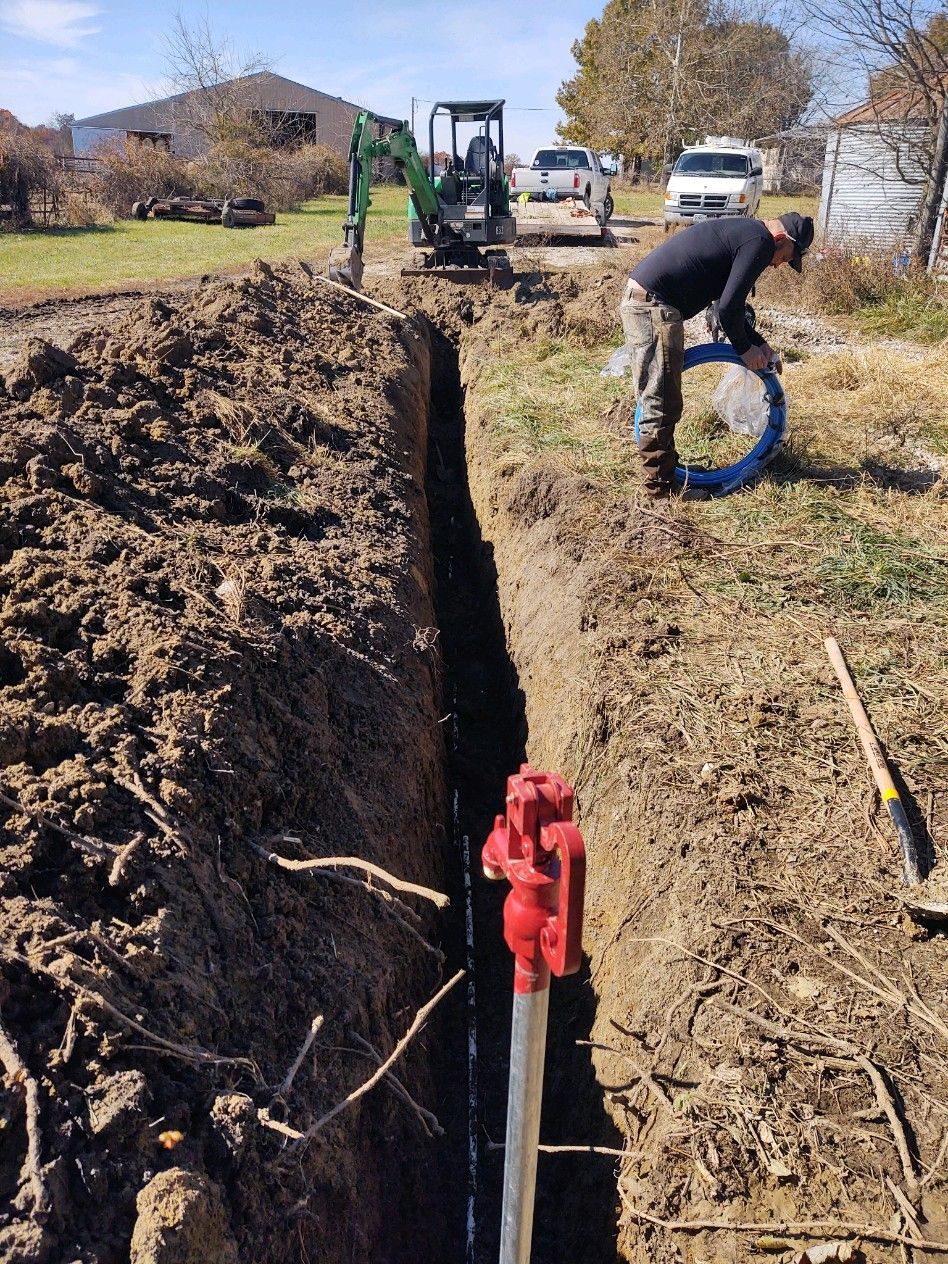 A man is digging a hole in the ground to install a pipe.