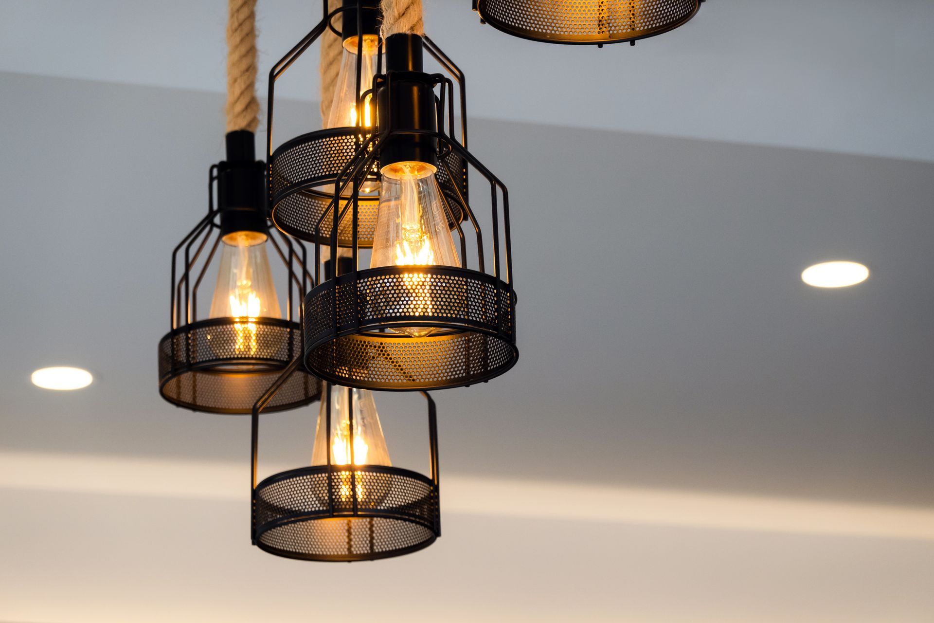 Close-up of a decorative pendant light fixture with multiple cage-shaped lights and exposed Edison bulbs.