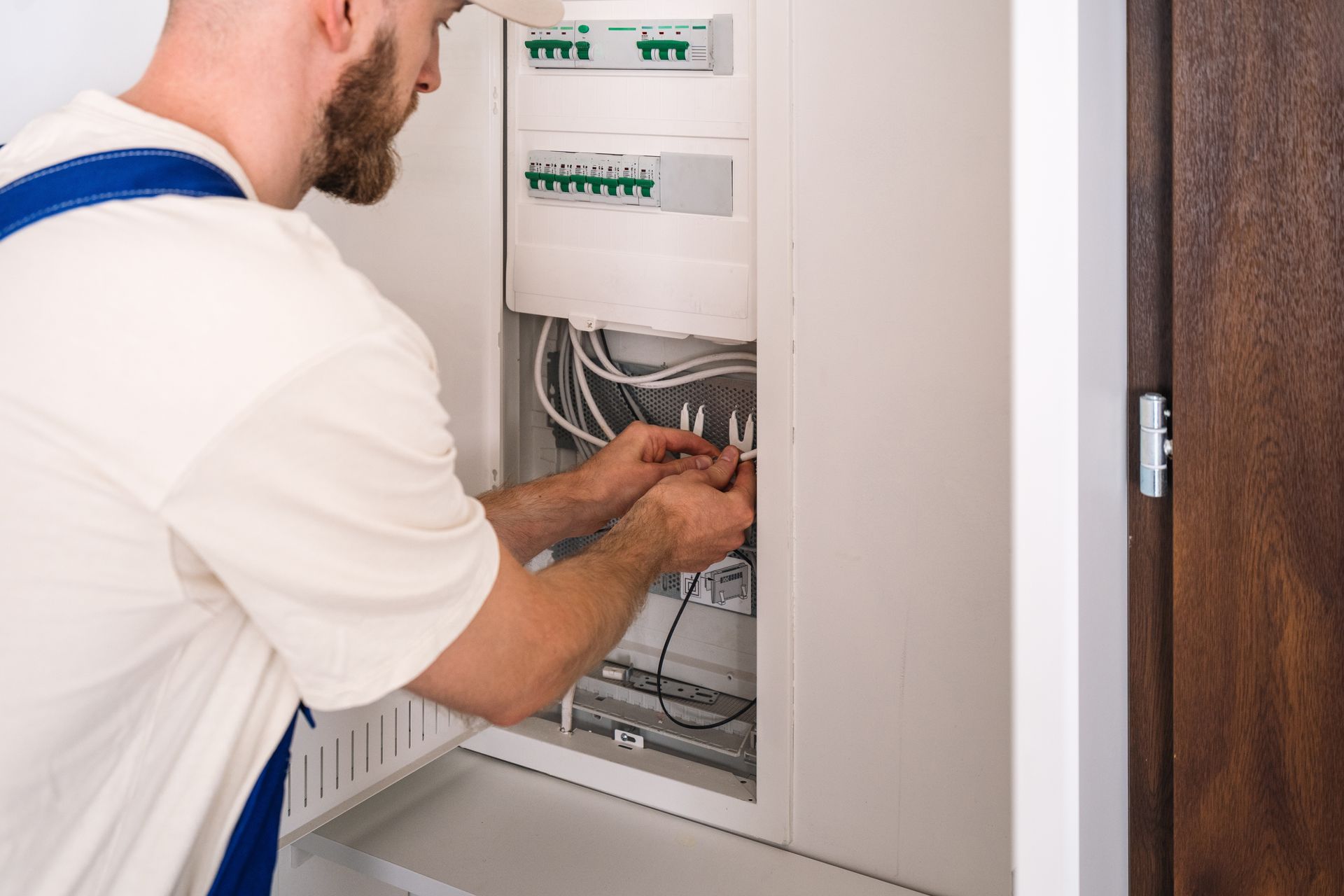 Electrician working on a circuit breaker panel, wiring connections.
