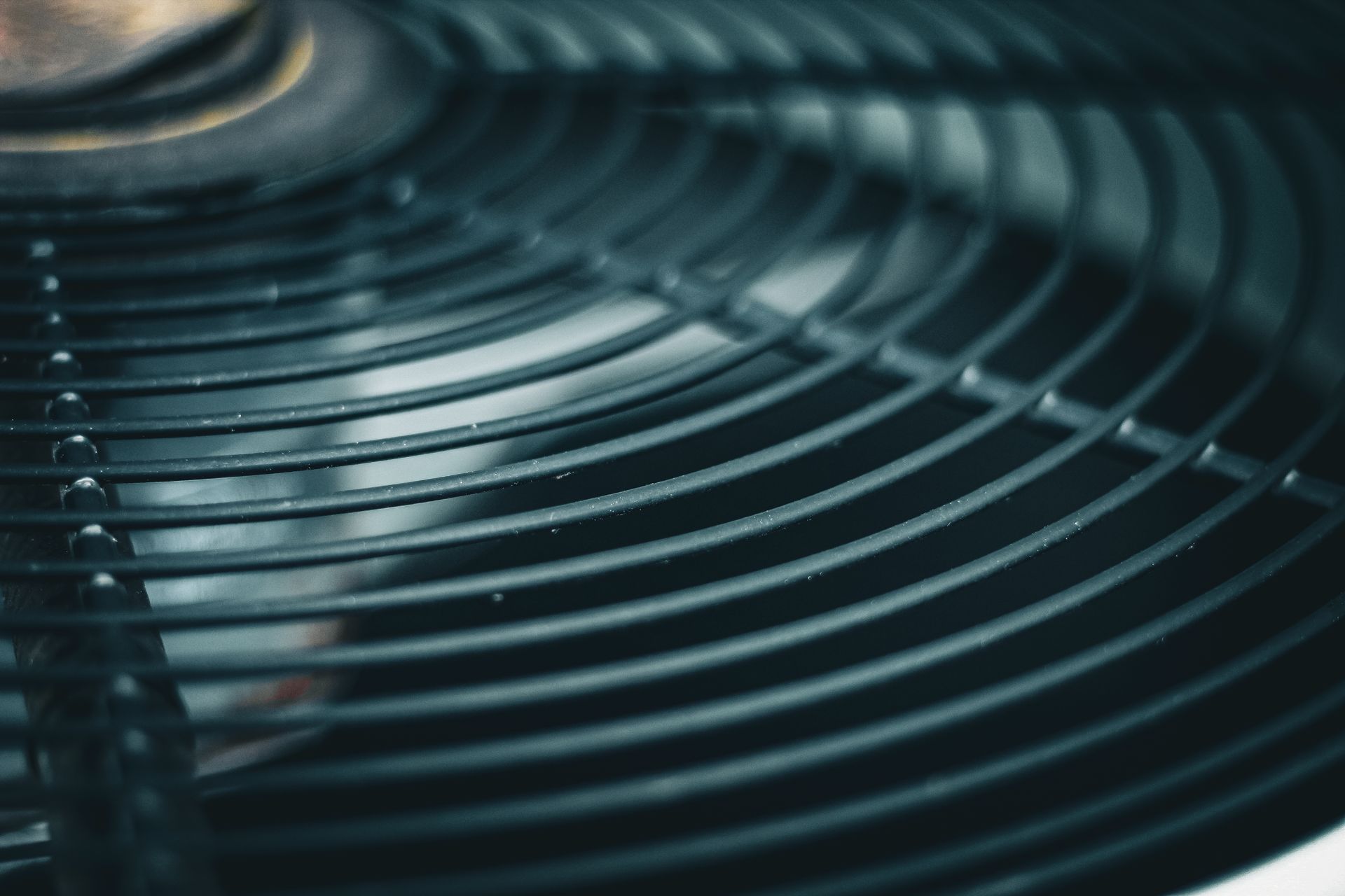 Close-up of a dark metal circular fan grille with concentric rings.