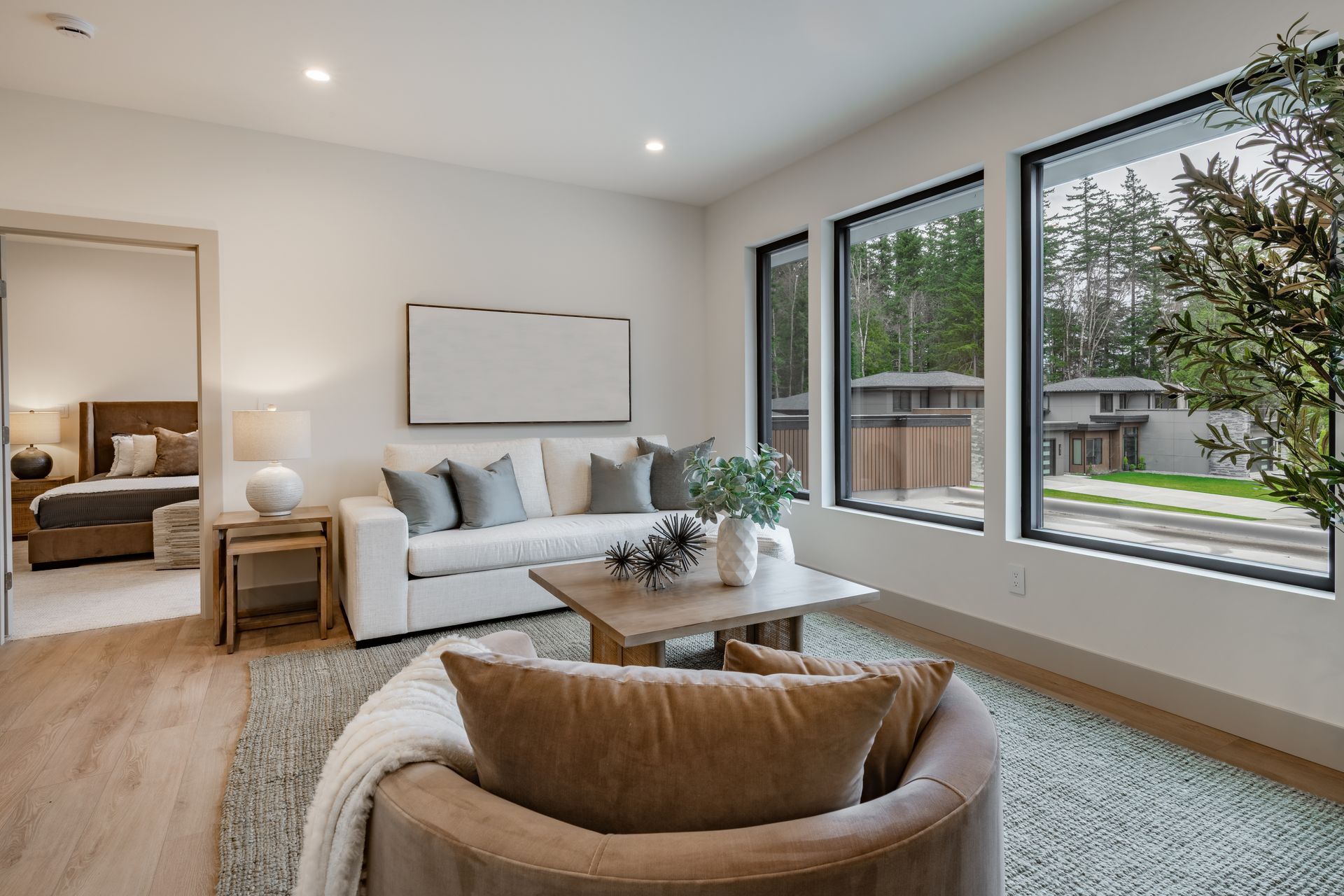Living room with white sofa, accent chair, coffee table, and large windows.