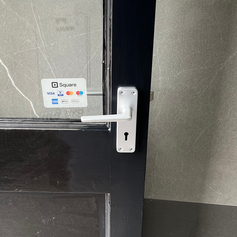 Black door with a silver handle and a Square payment sticker.