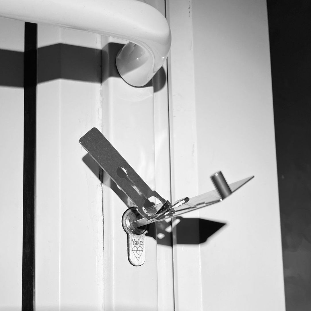 Metal latch and handle on a white door, casting shadows.