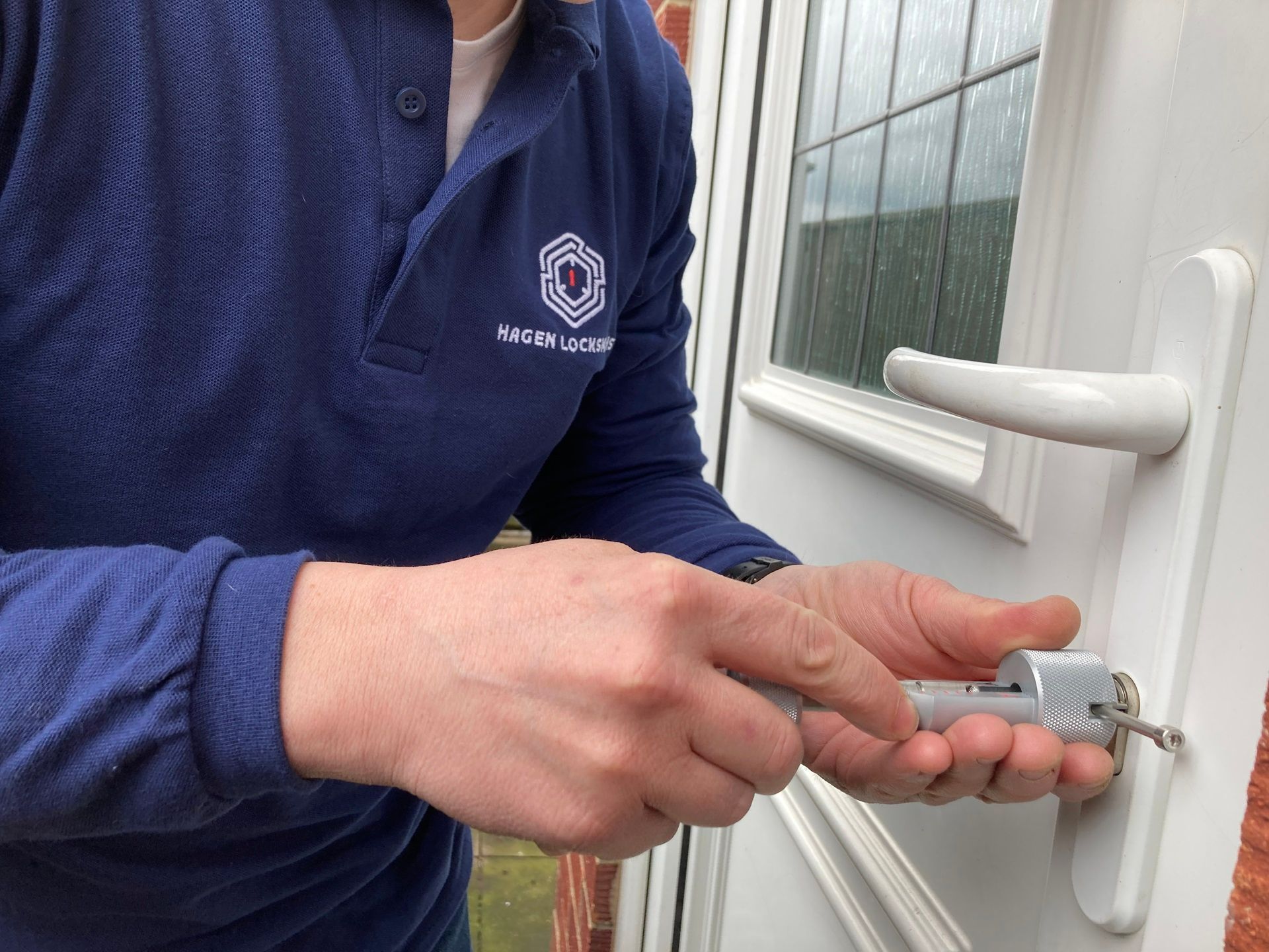 Locksmith using tools to repair a door lock on a white door.