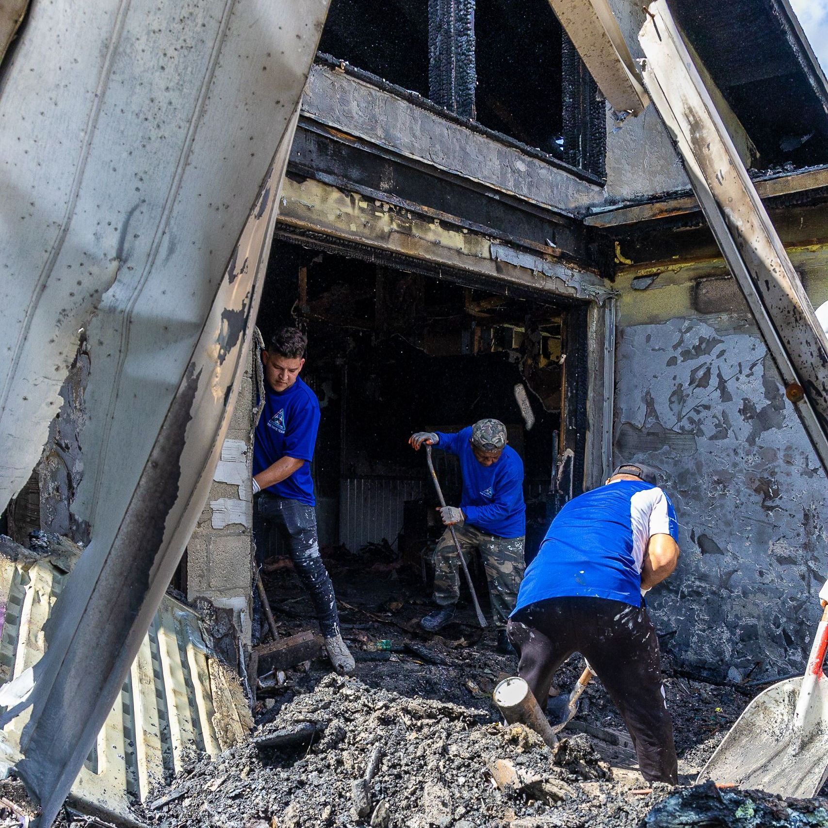 A group of men in blue shirts are working on a building