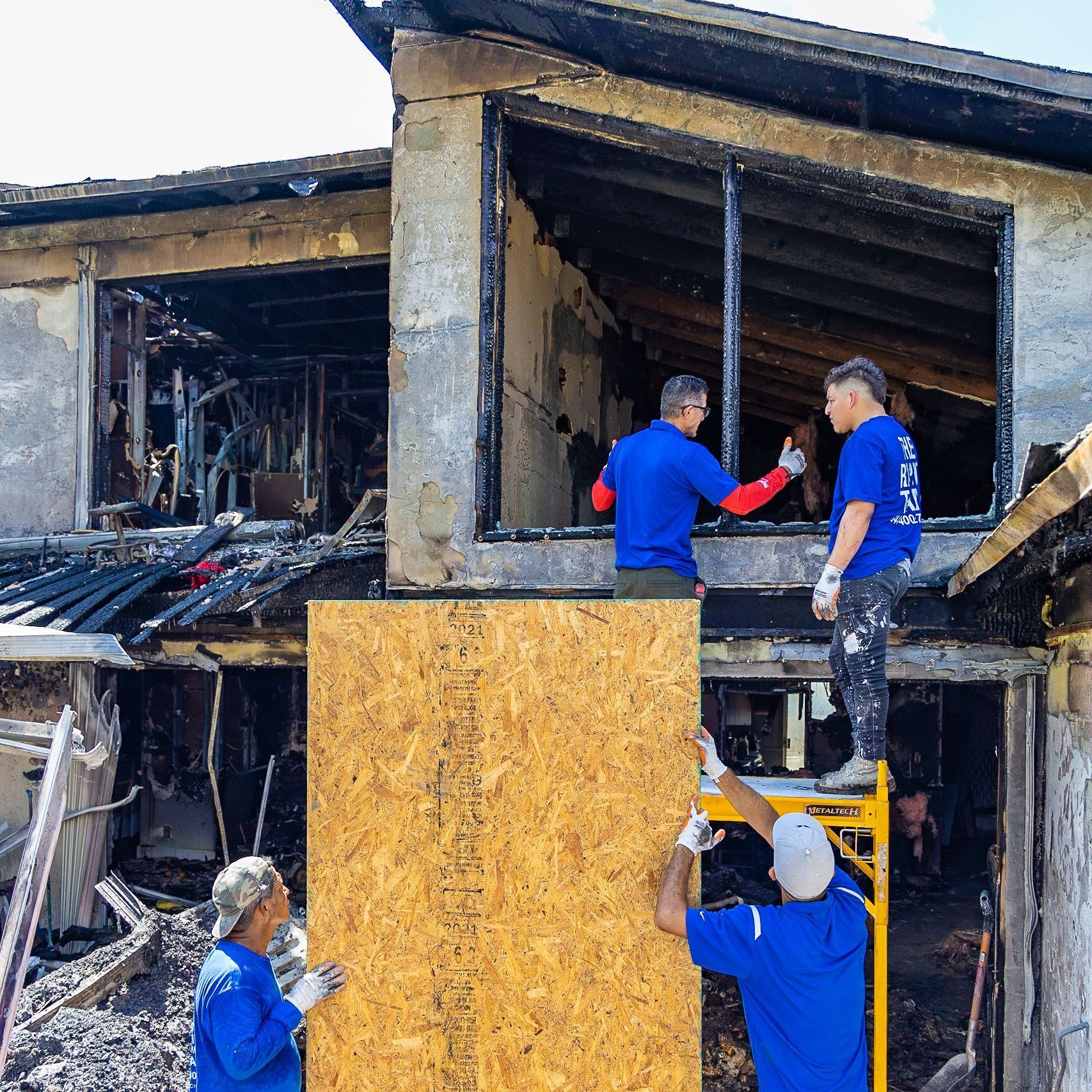 A group of men are working on a building that has been damaged by a fire.