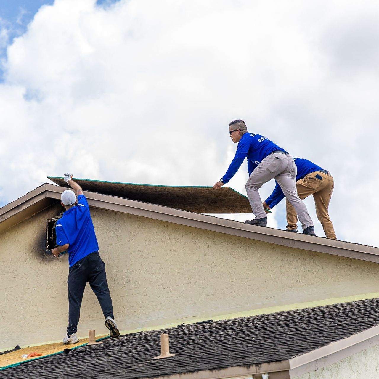 Two men are working on the roof of a house.