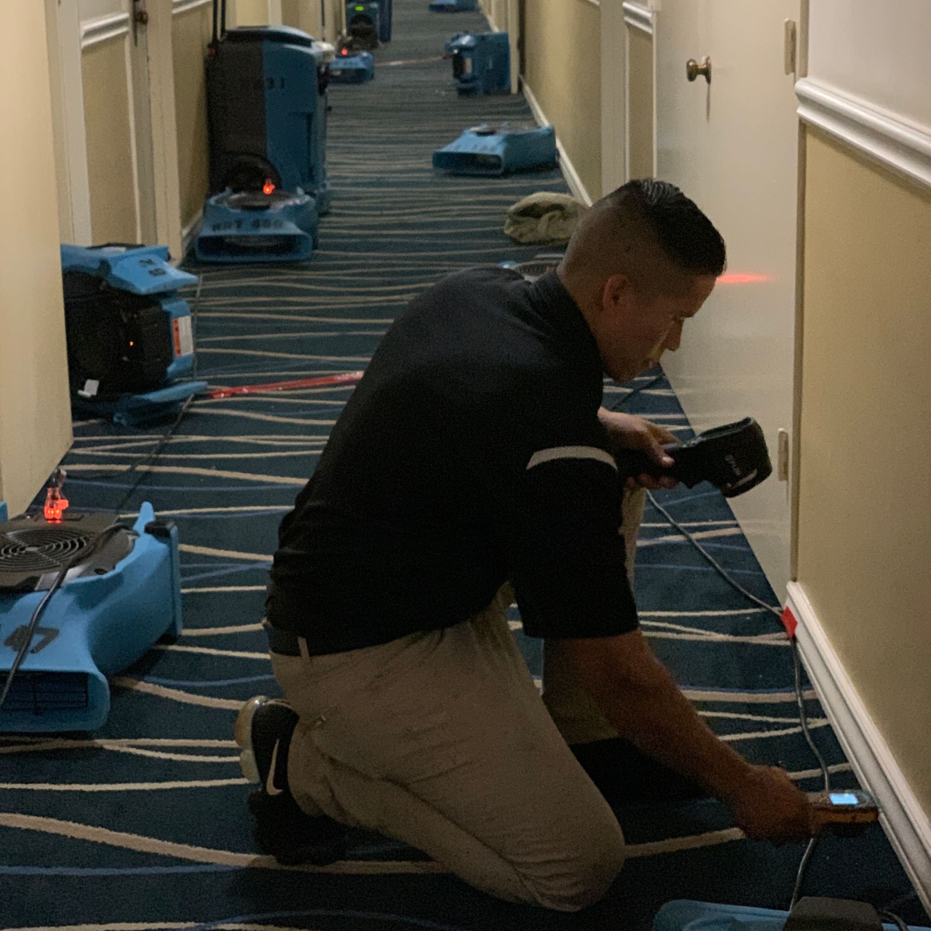 A man is kneeling down in a hallway holding a camera