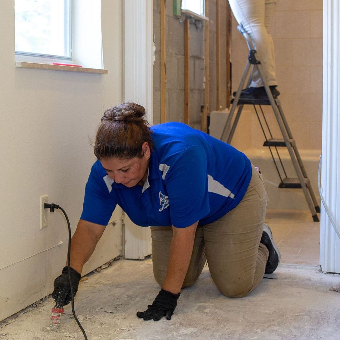 A woman in a blue shirt is working on a wall