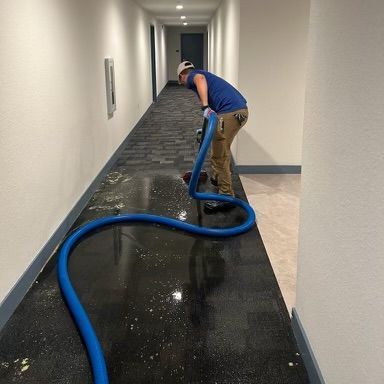 A man is using a vacuum cleaner to clean a hallway.