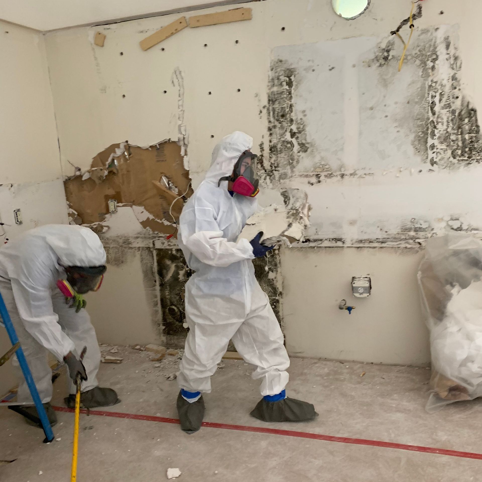 Two men in protective suits are working in a room