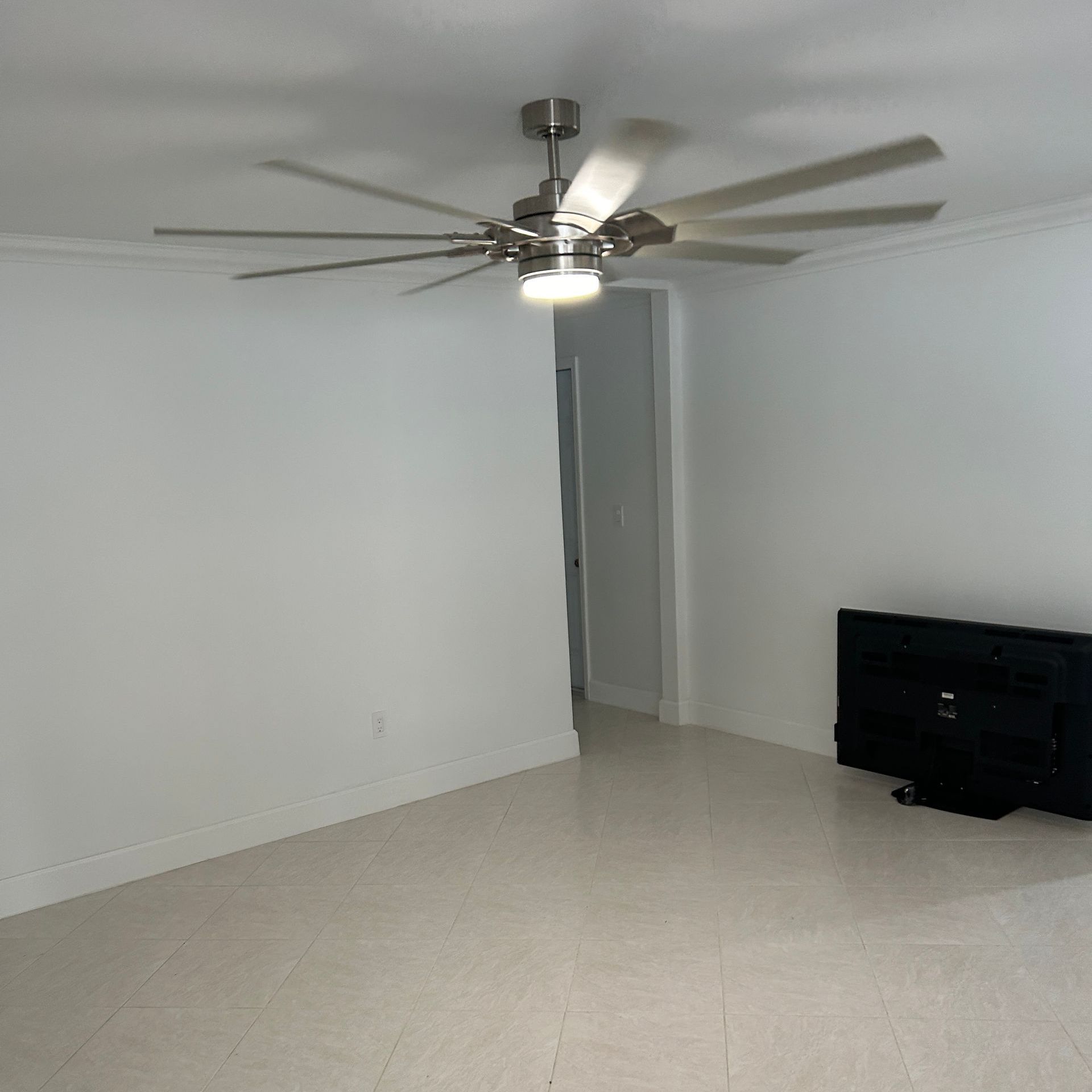 An empty room with a ceiling fan and a television