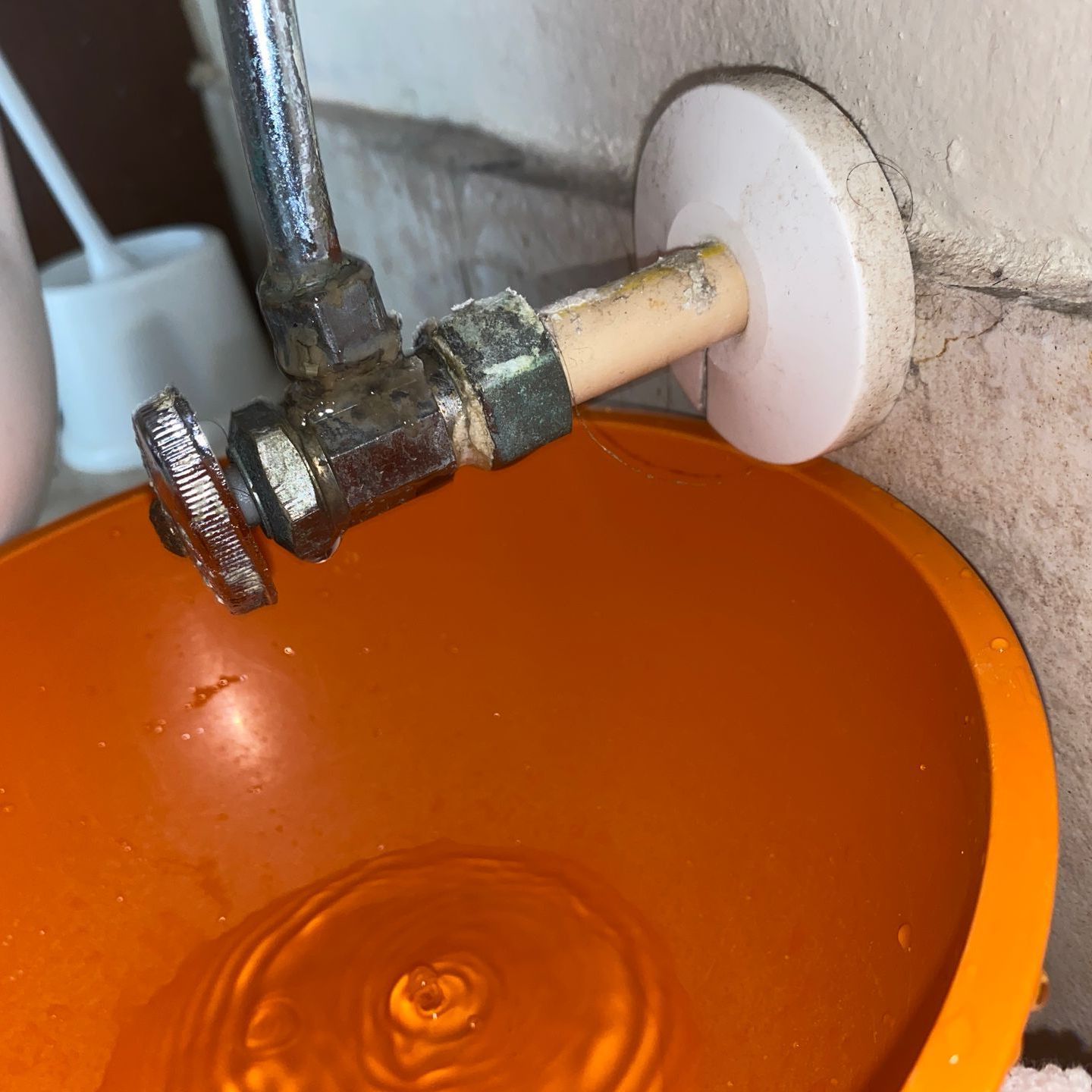 A close up of a faucet in an orange bowl