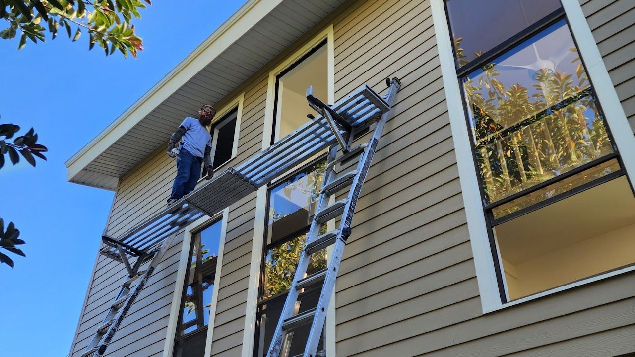 Technicians securing storm shutters over hurricane windows on second-story home