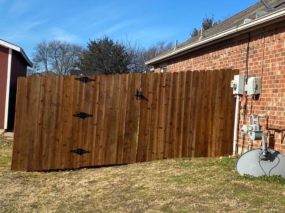 A wooden fence with a gate in front of a brick house.