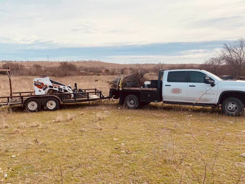 A white truck is towing a trailer in a field.