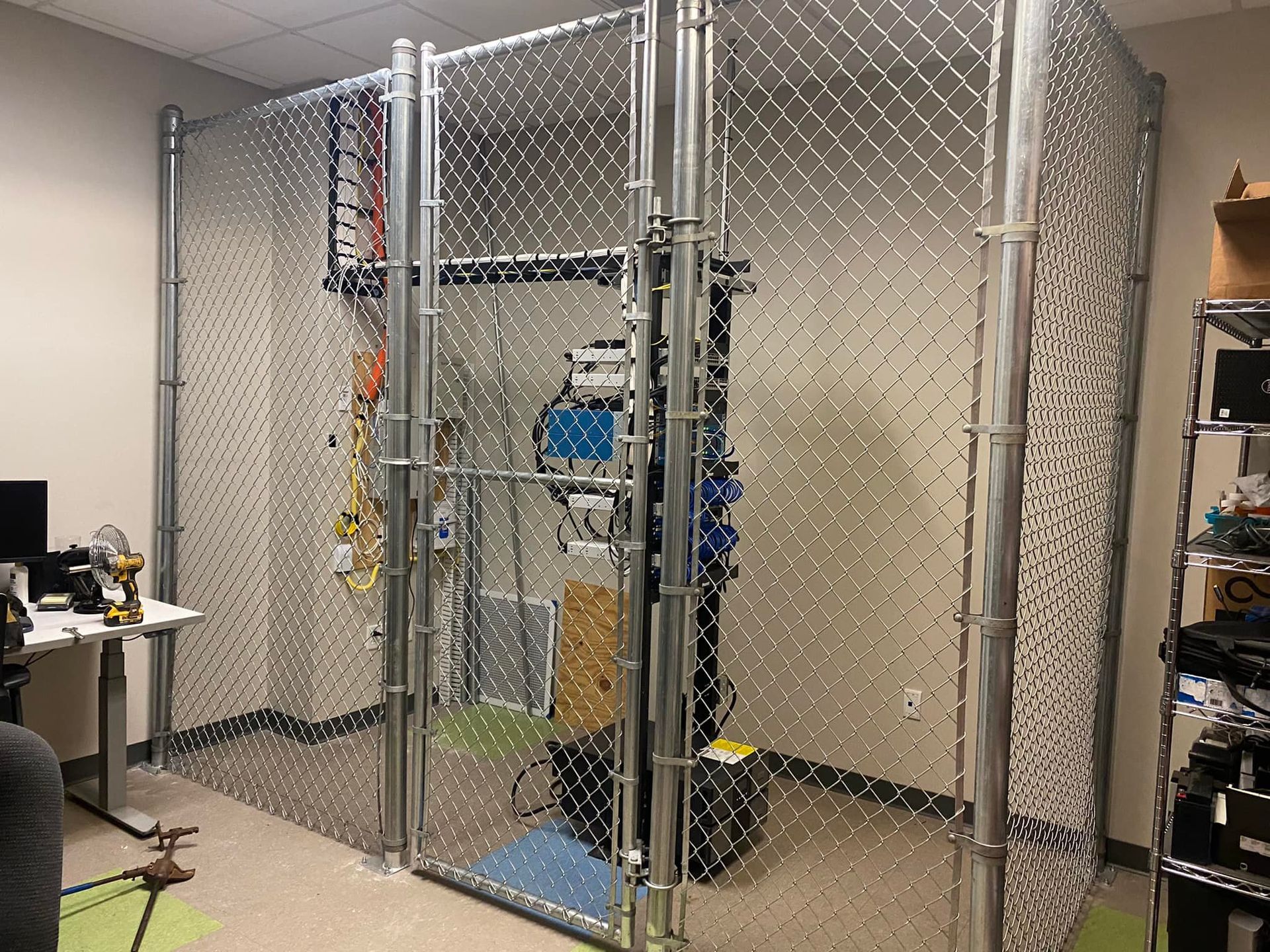 A room with a chain link fence and a desk.
