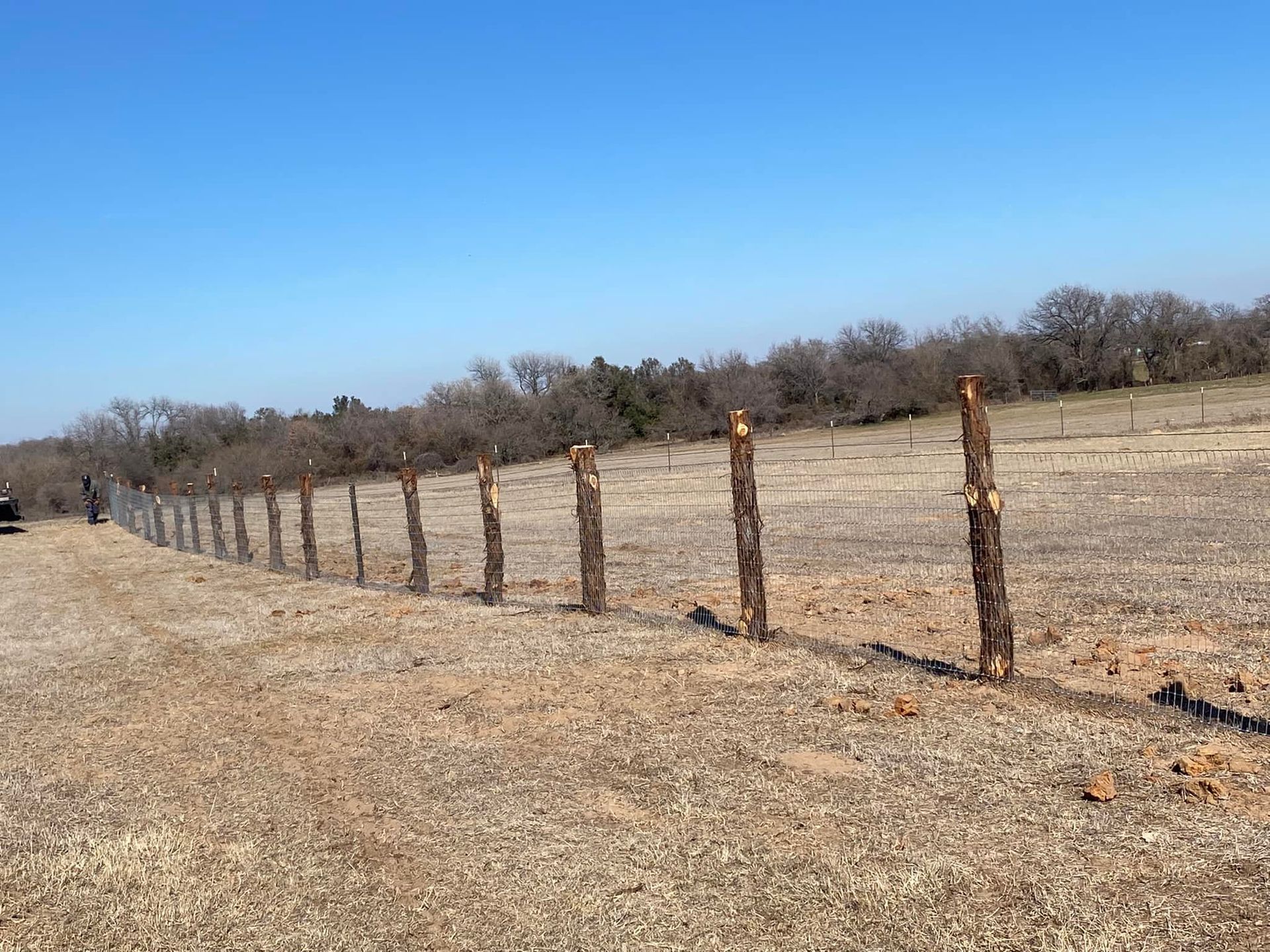 A row of barbed wire fences along a dirt road