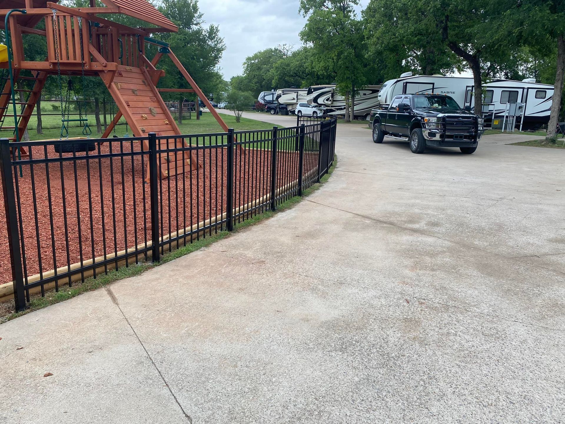 A black truck is parked in a parking lot next to a playground.