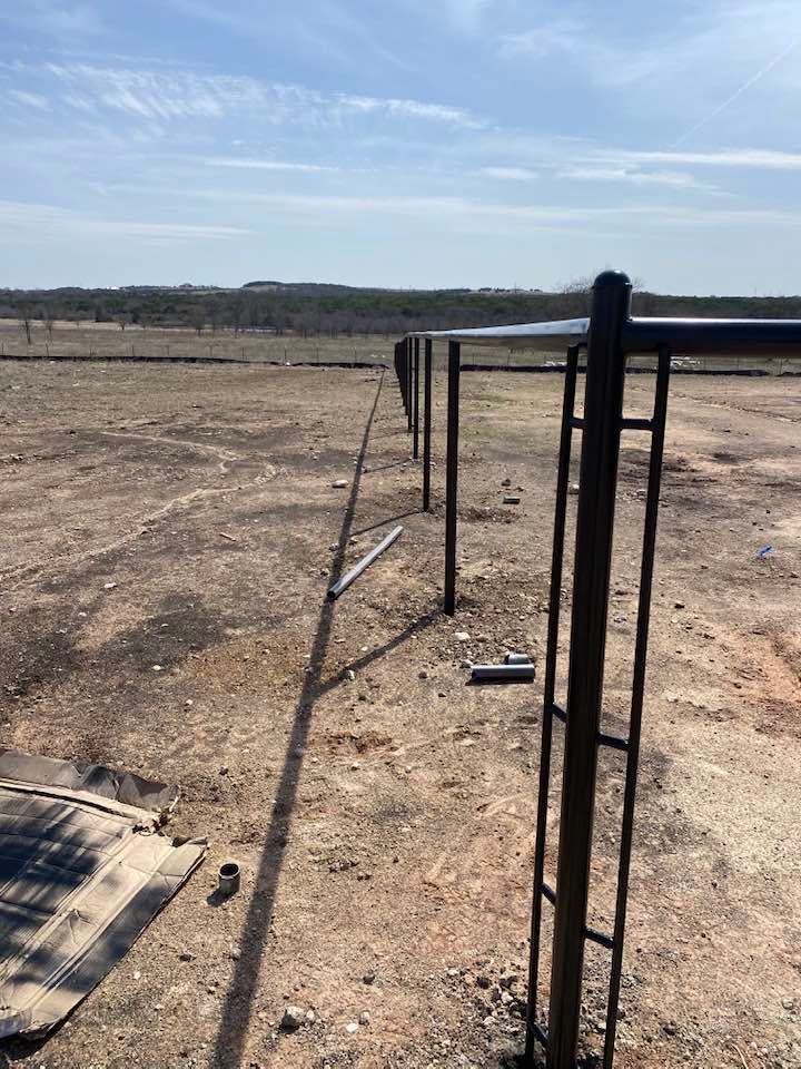 A fence is being built in the middle of a dirt field.