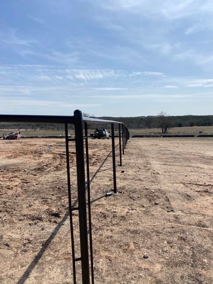 A fence is being built in the middle of a dirt field.