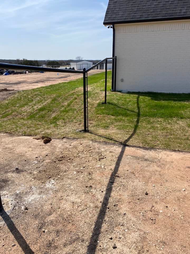 A shadow of a fence is cast on the ground in front of a house.