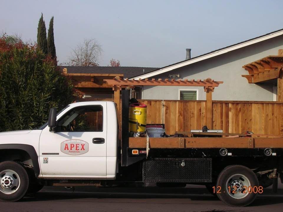 A white apex truck is parked in front of a house
