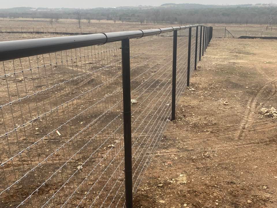 A barbed wire fence is surrounding a dirt field.