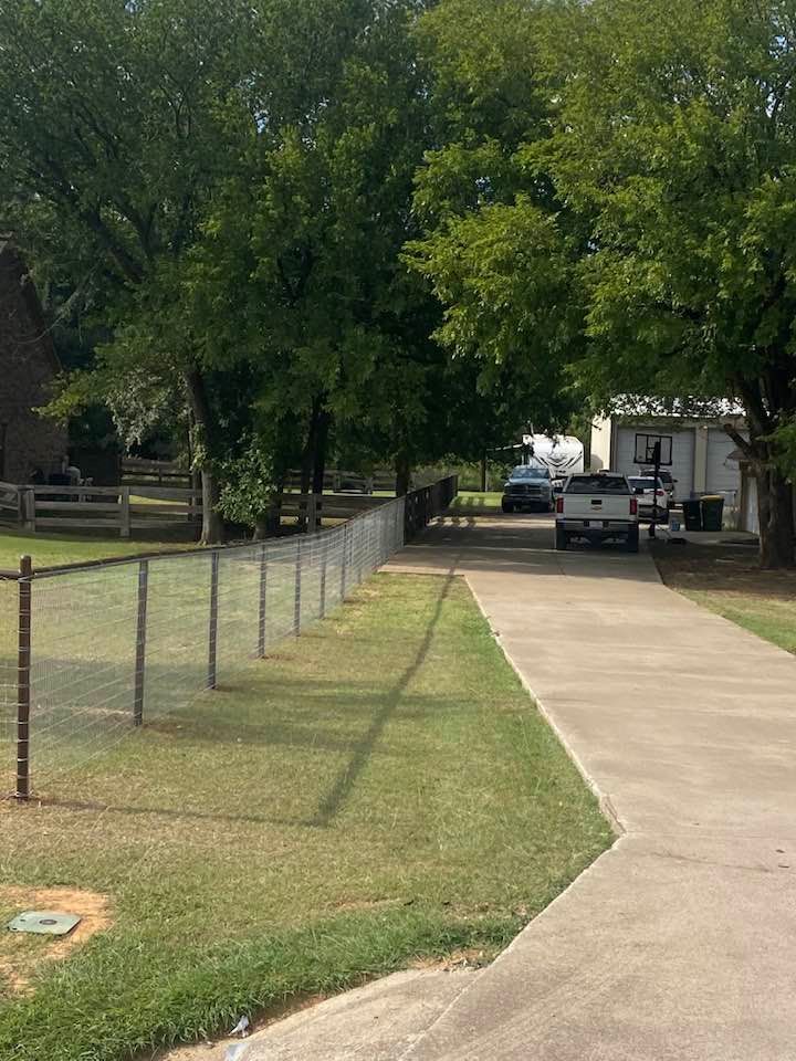 A white truck is parked in a driveway next to a fence.