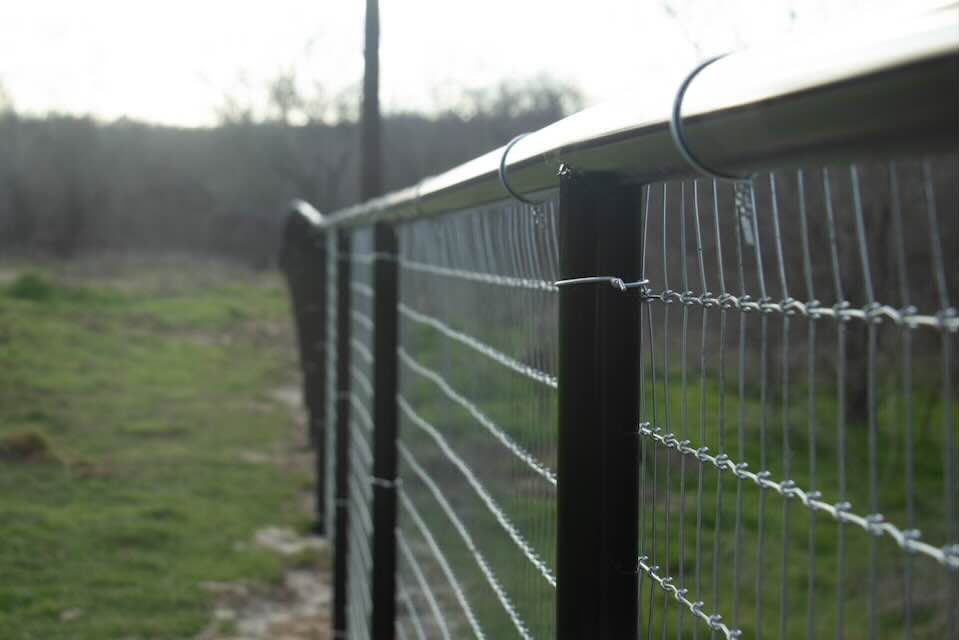A barbed wire fence is surrounding a grassy field.