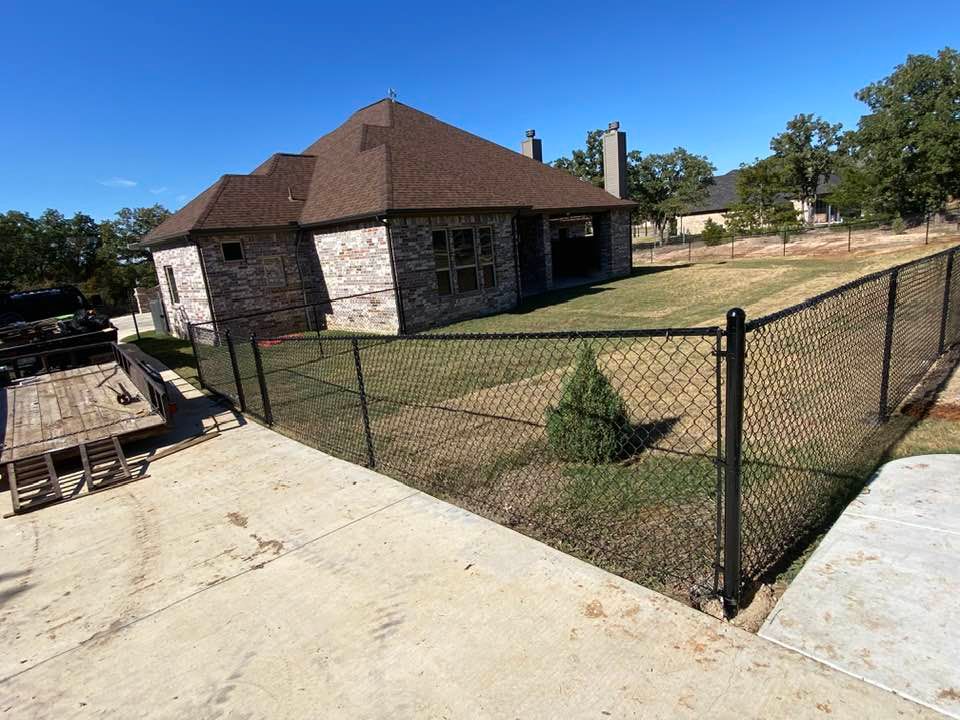 A black chain link fence surrounds a large house.