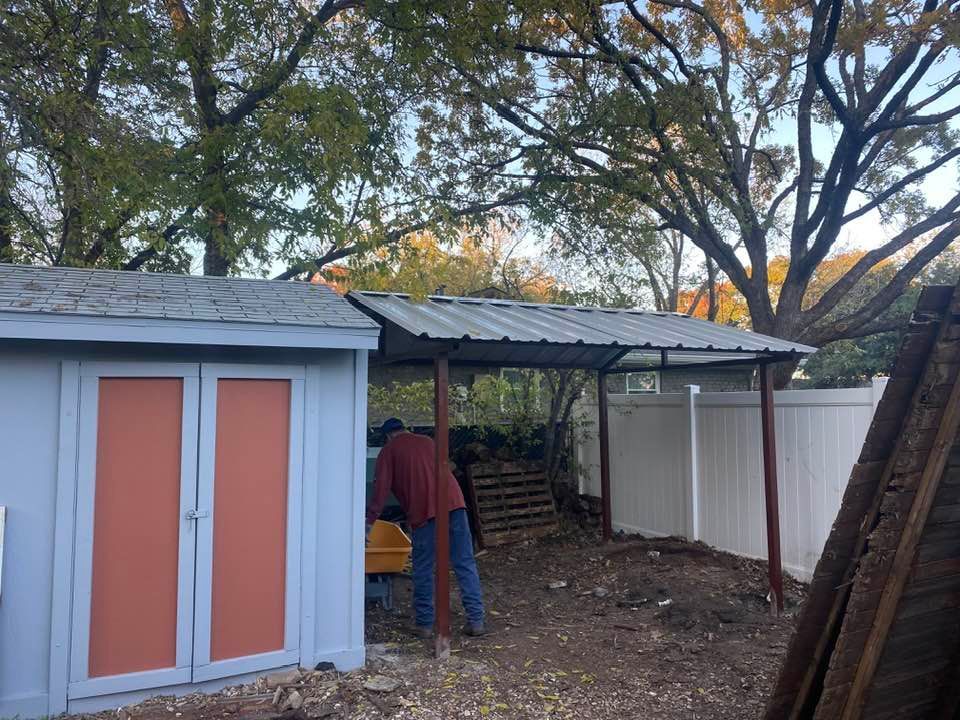 A man is standing in front of a shed with a metal roof.