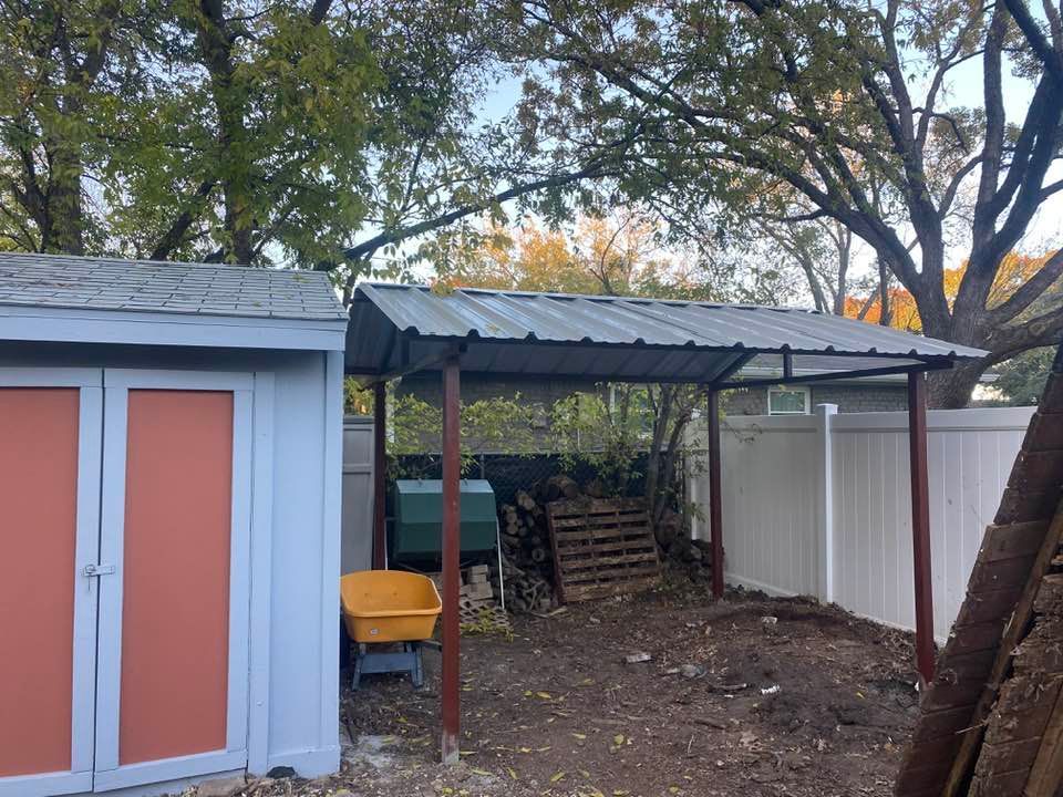 A shed with a metal roof and a wheelbarrow in the backyard.