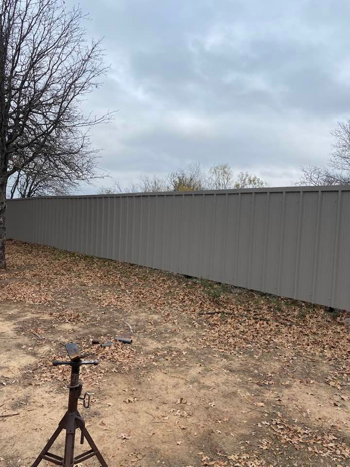 There is a fence in the background and a tree in the foreground.