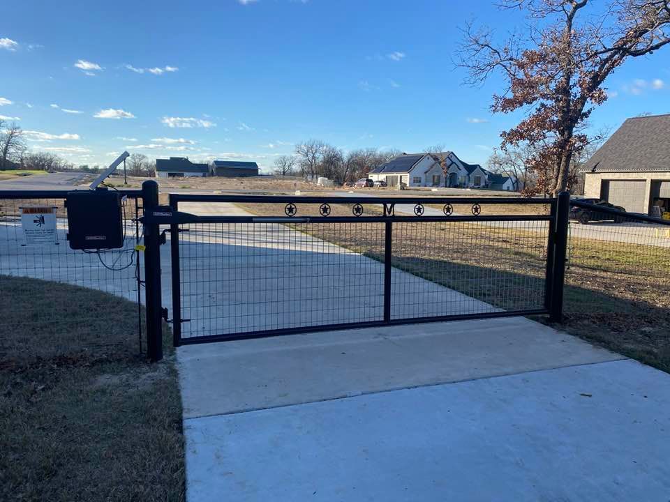 A black gate is sitting on top of a concrete driveway next to a house.