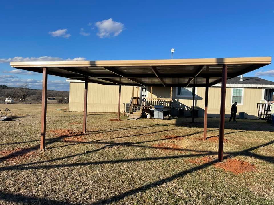 A carport is sitting in the grass in front of a house.