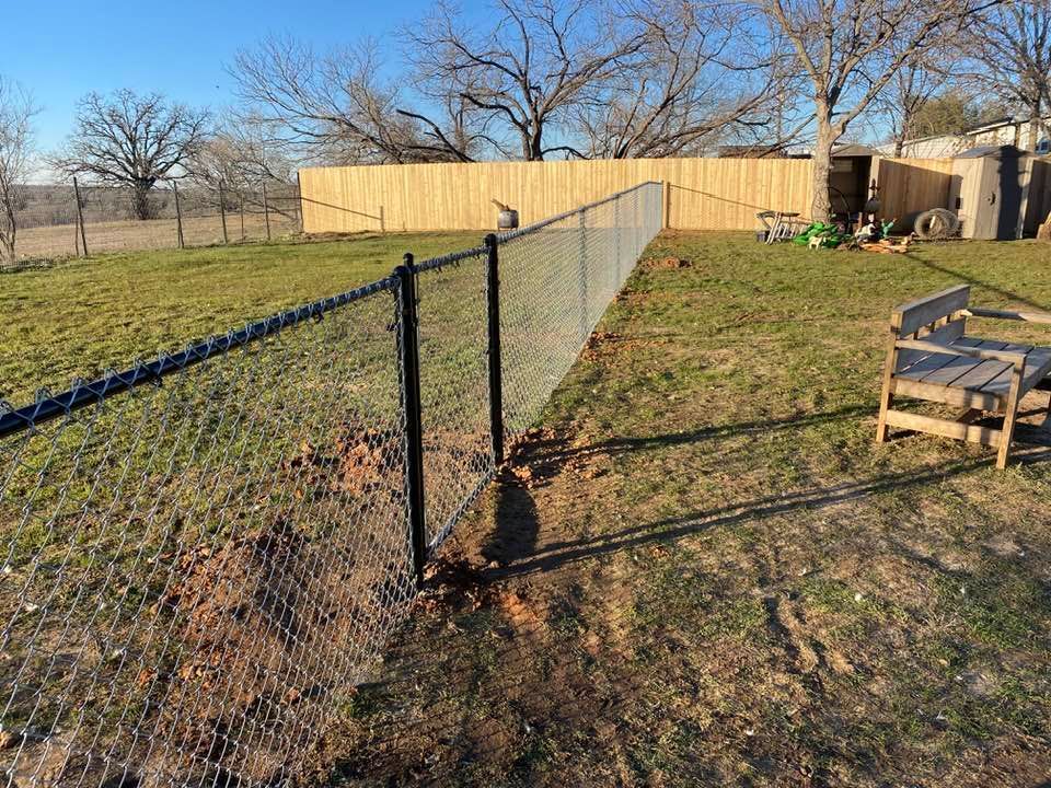 A chain link fence is sitting in the middle of a grassy field.