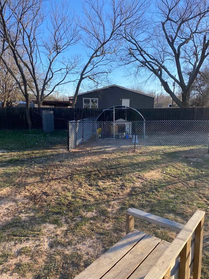 A backyard with a wooden bench and a chain link fence.