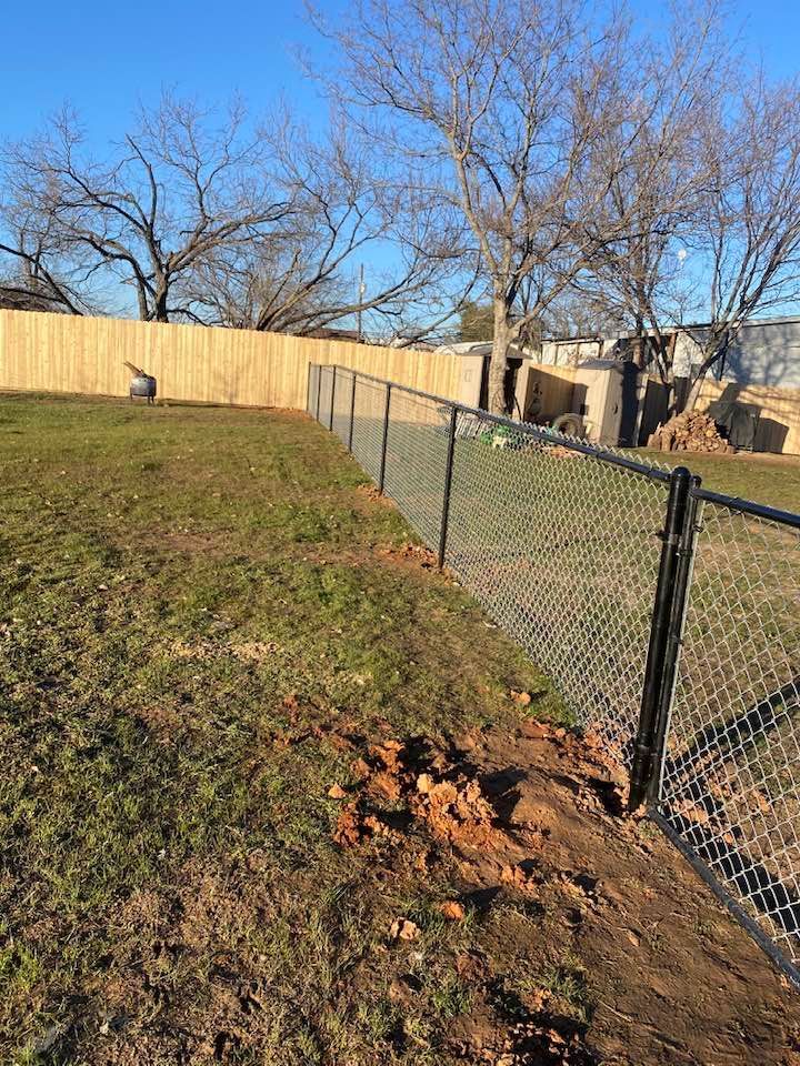 A chain link fence is sitting in the middle of a grassy field.
