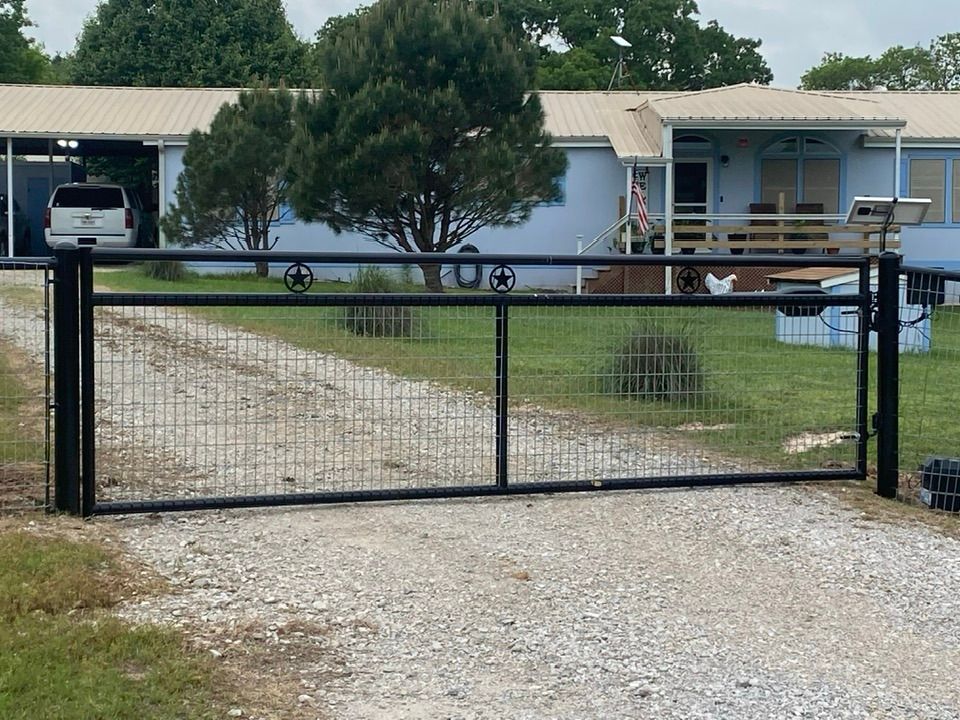 A driveway with a fence and a house in the background