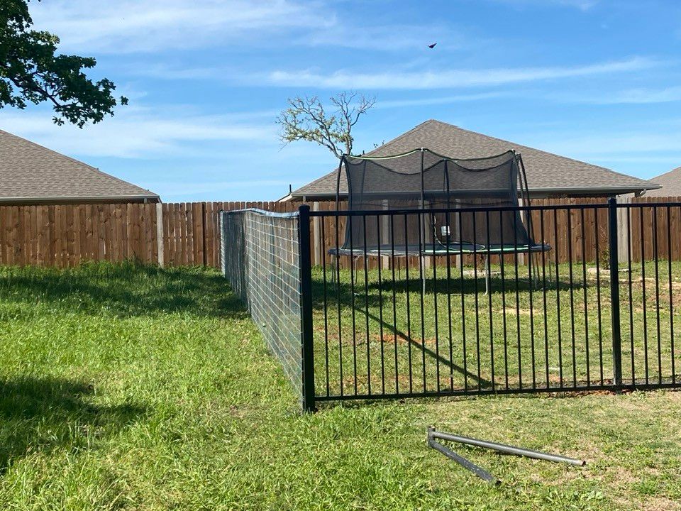 There is a trampoline in the backyard behind a fence.
