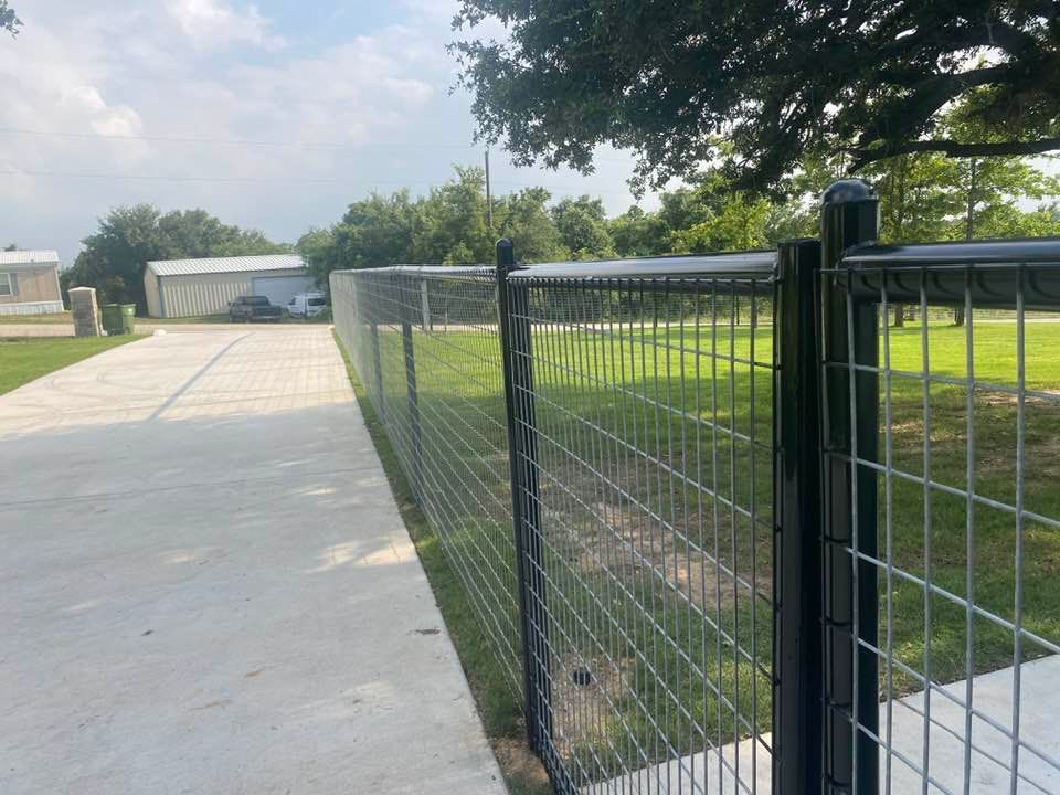 A black wire fence is along the side of a road.