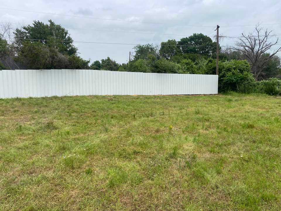 A large grassy field with a white fence in the background.