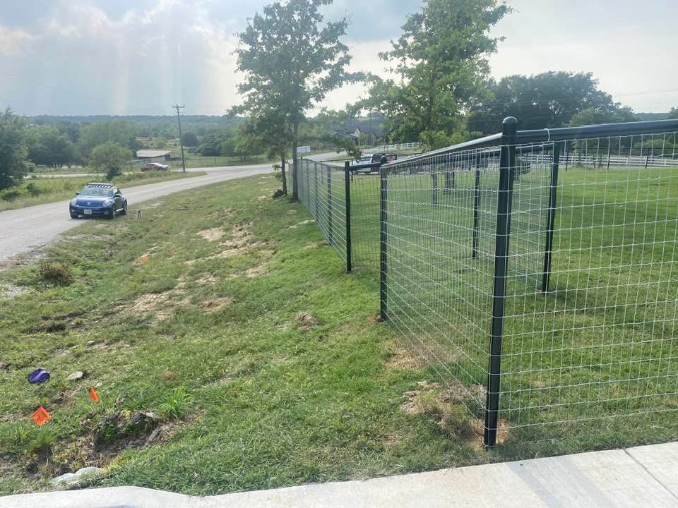 A car is driving down a road next to a fence.