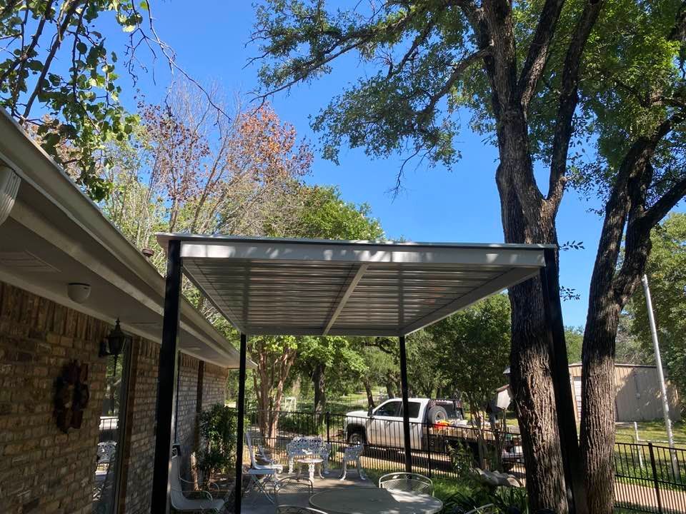 A carport is sitting in front of a brick house.