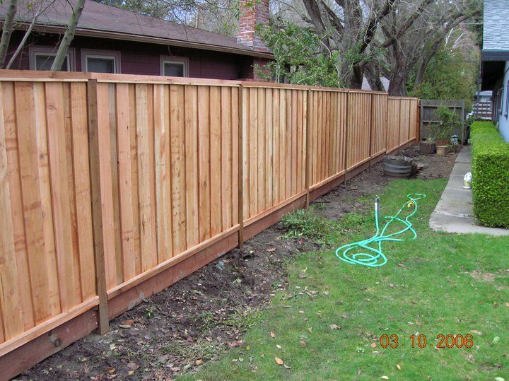 A wooden fence is in the backyard of a house.