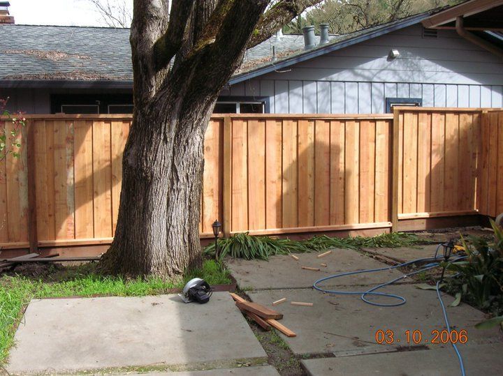 A wooden fence is being built in the backyard of a house.
